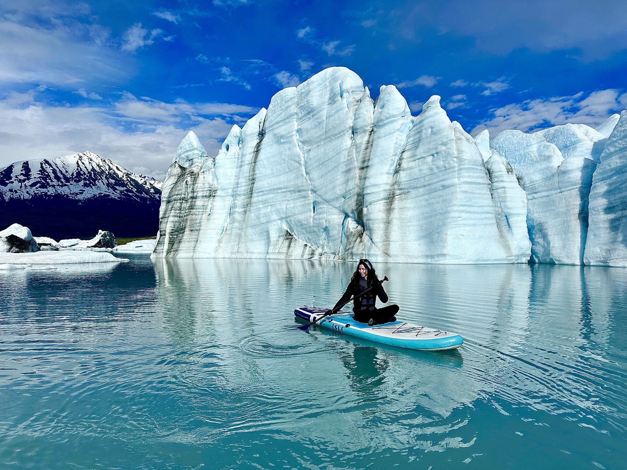 Mona paddleboarding beside blue glacial ice